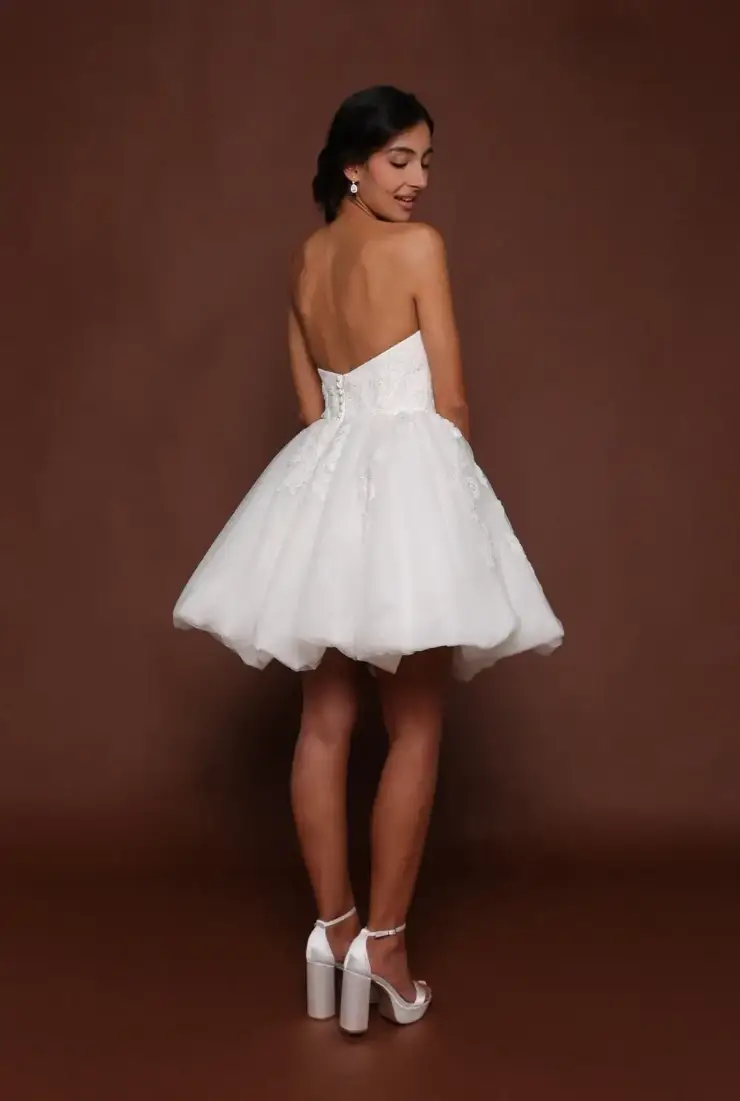 Model is wearing a mini wedding dress with a sweetheart neckline and a bubble hem by robert bullock