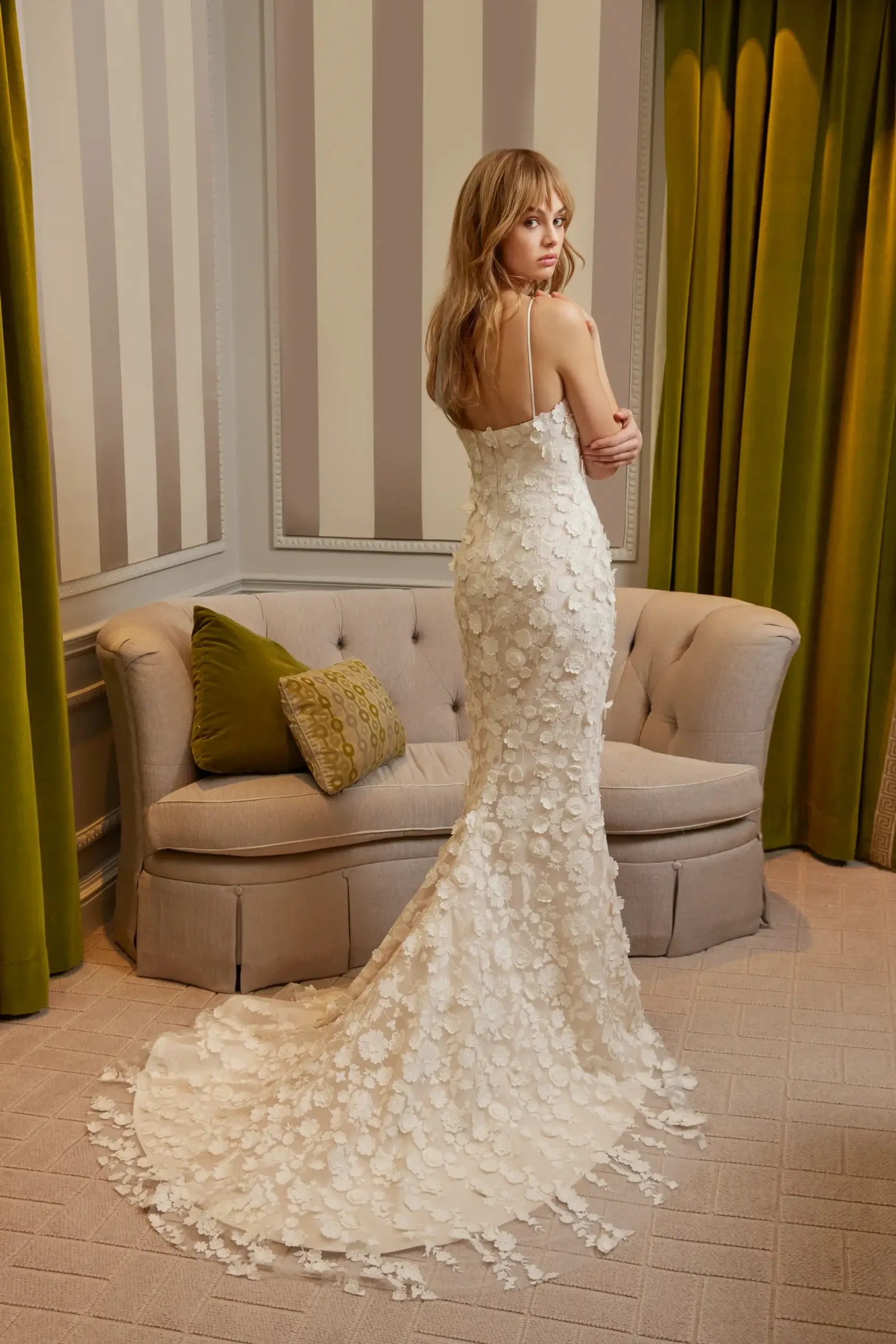 Model is wearing a sleeveless fit and flare wedding dress with spaghetti straps and 3D florals