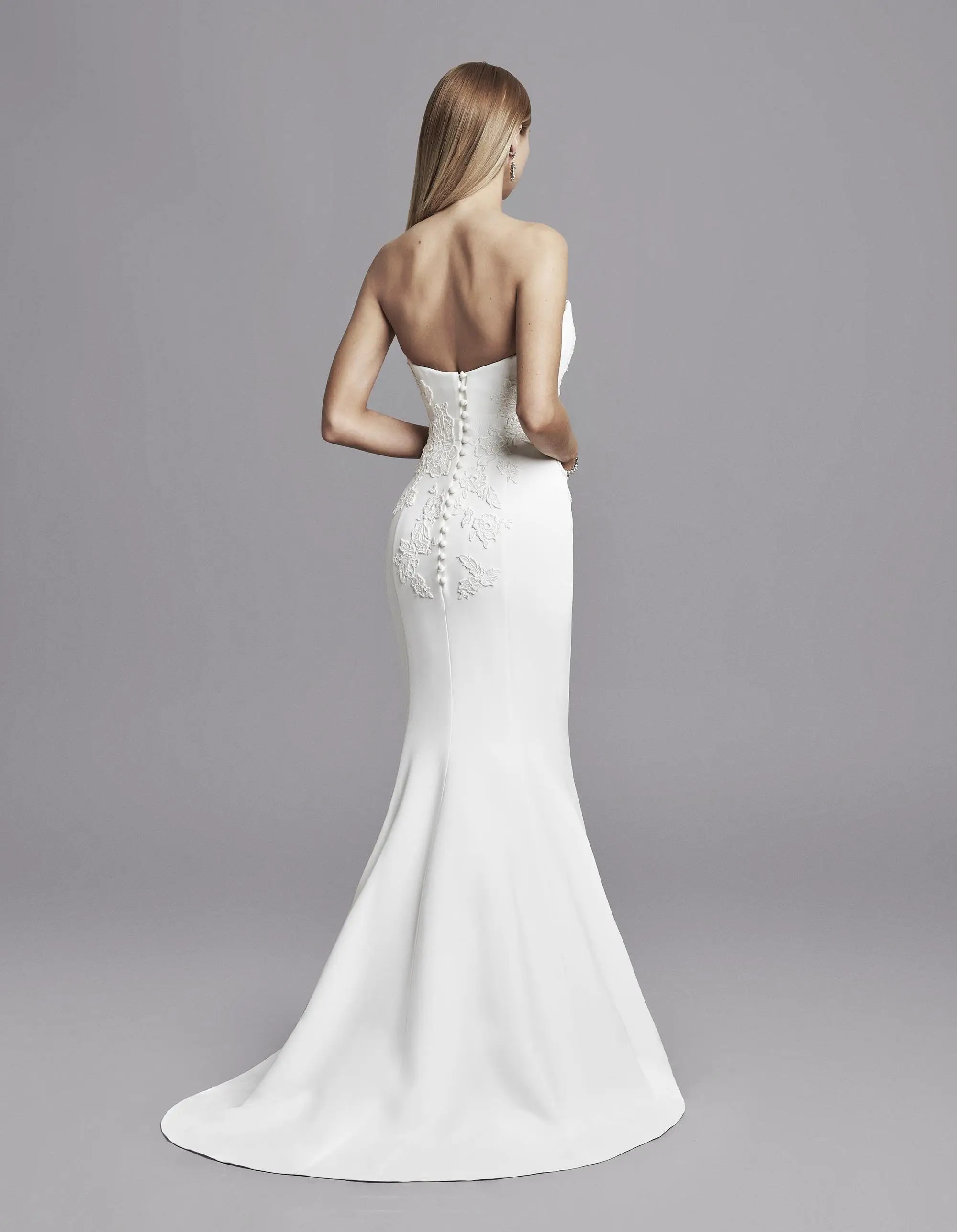 Model is wearing a strapless fit and flare wedding dress by caroline castigliano 
