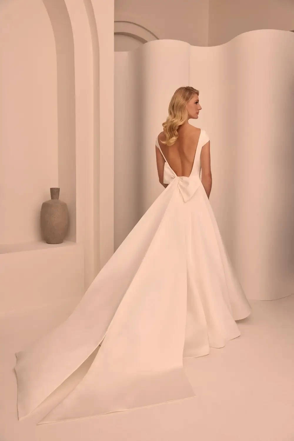 model is wearing a sleeveless minimalist bridal gown