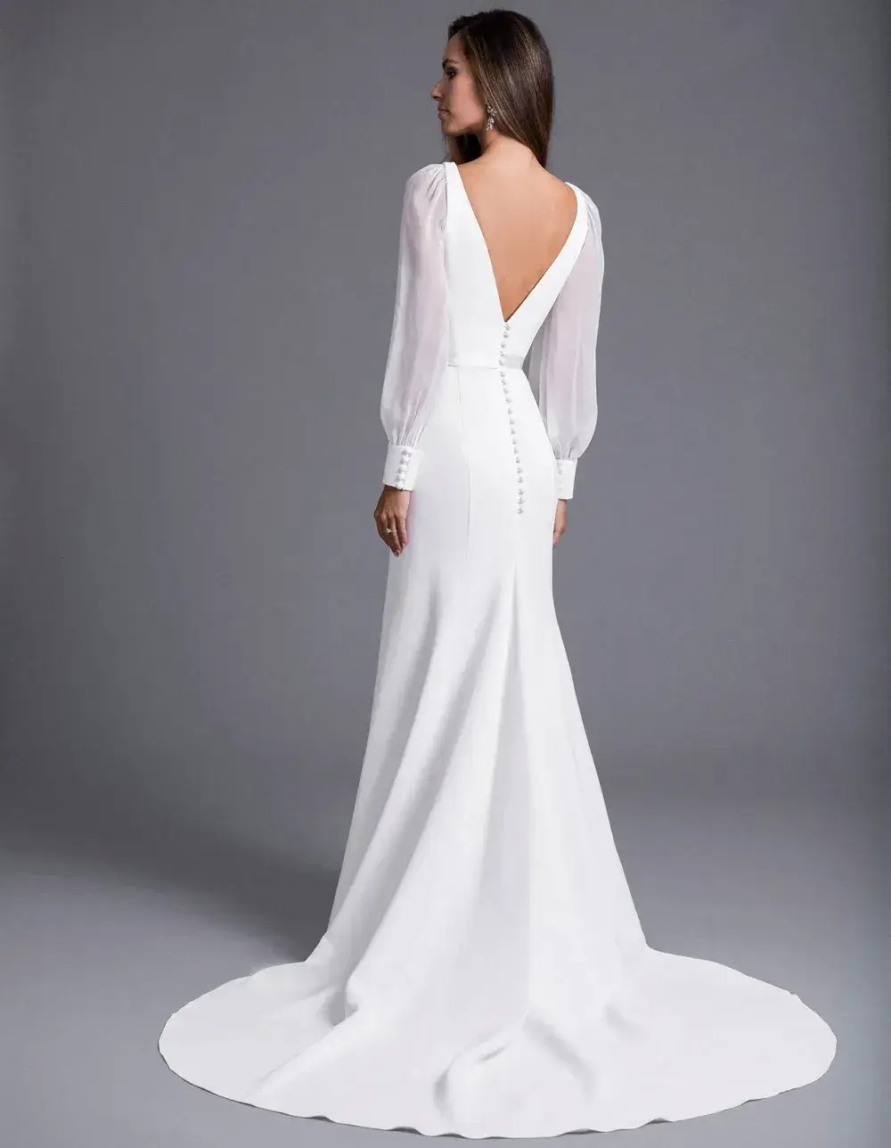 Model is wearing a fit and flare wedding dress with billowy sleeves by caroline castigliano 