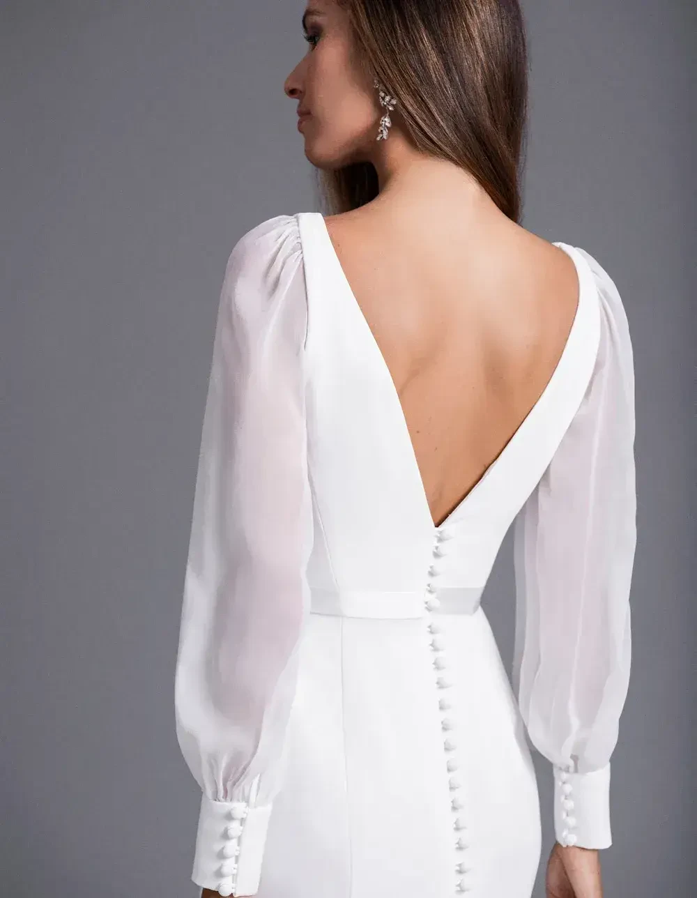 model is wearing an open back long sleeve bridal gown