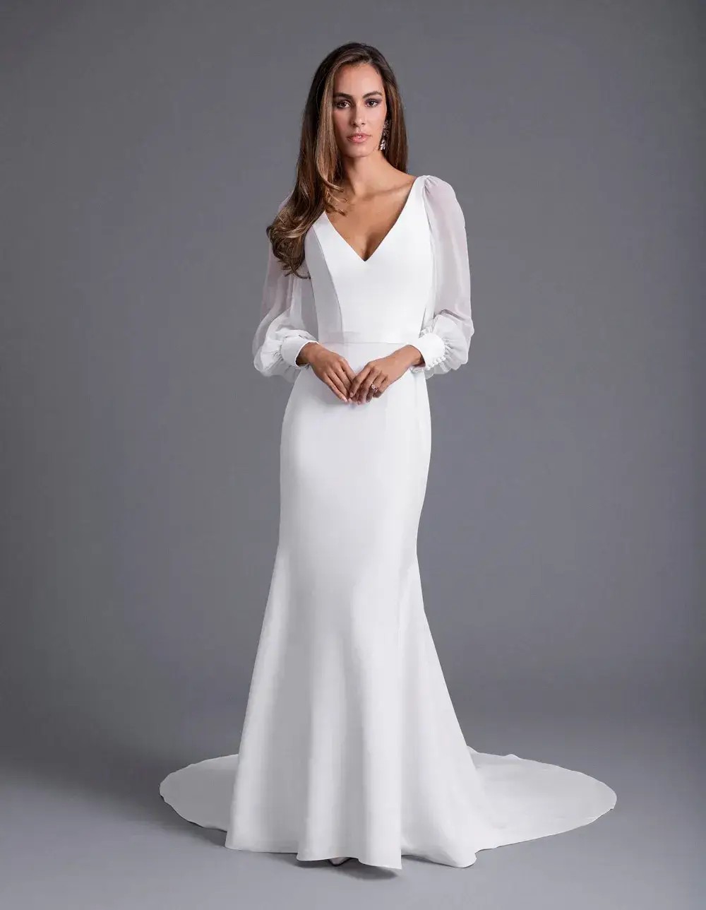 Model is wearing a fit and flare wedding dress with billowy sleeves by caroline castigliano 