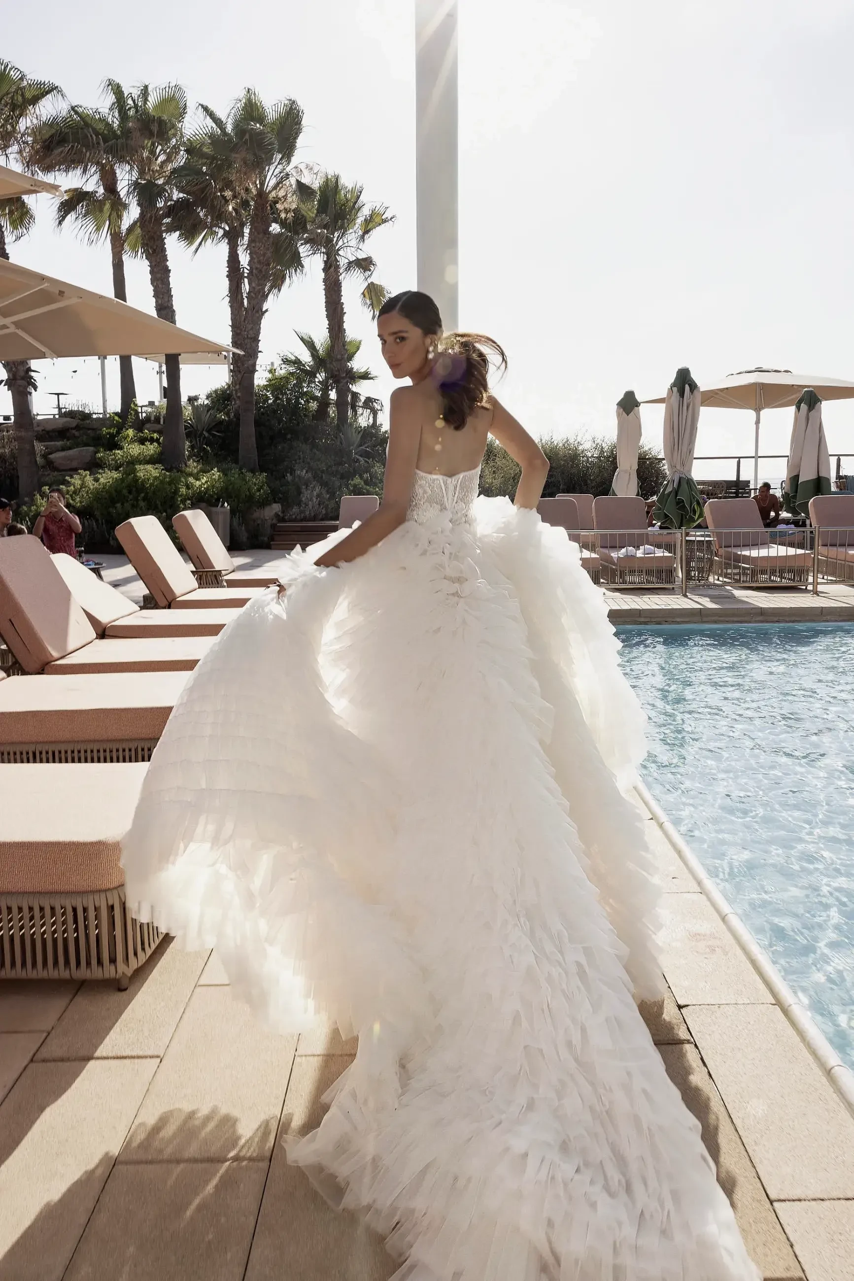 Model is wearing a wedding dress with a detachable overskirt, plunging neckline, and 3D floral lace by gabrielle atelier 
